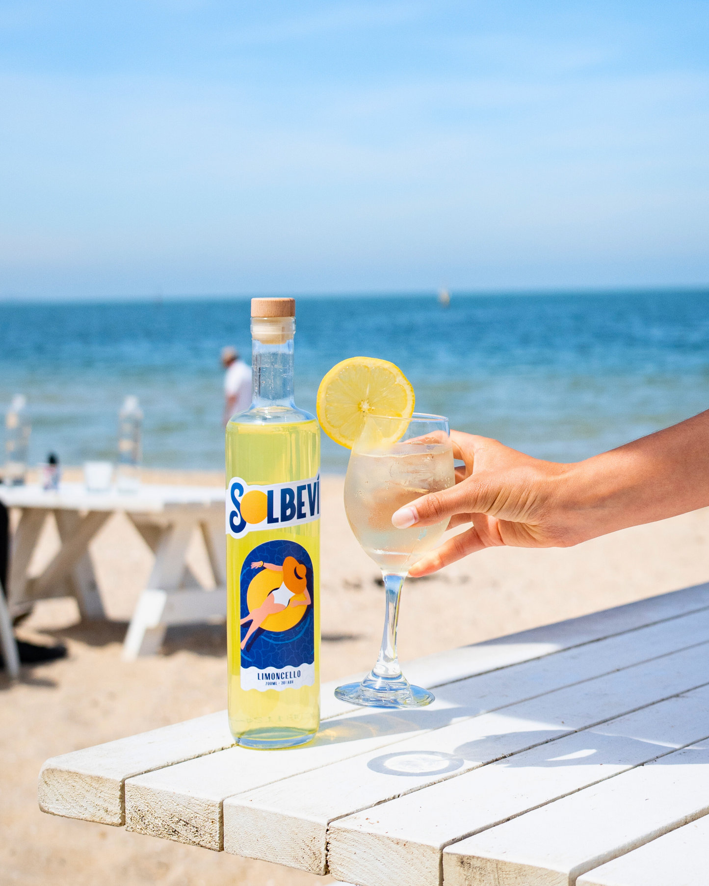 Solbevi Limoncello bottle and glass with lemon garnish on the beach