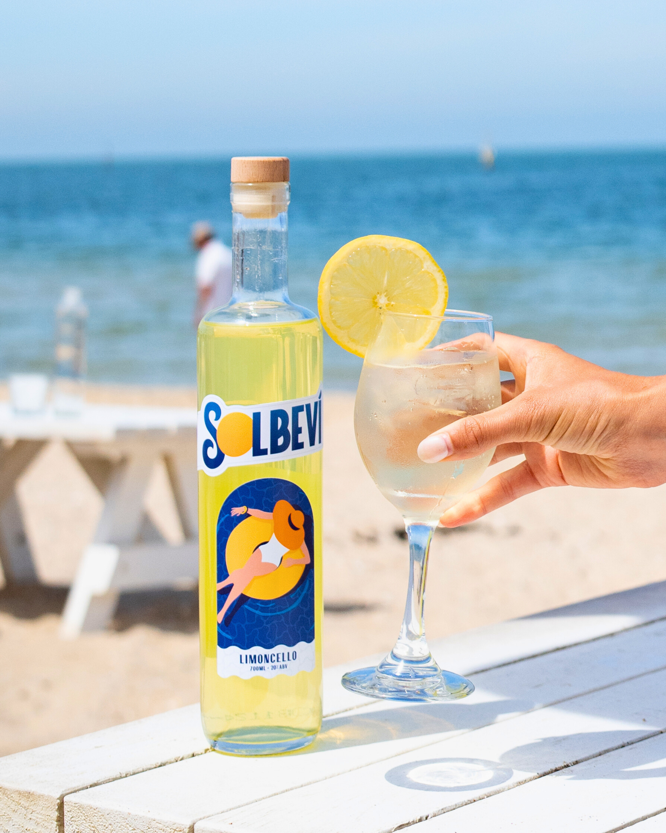 Solbevi Limoncello bottle and glass with lemon garnish on the beach